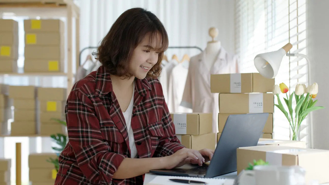 A woman on a laptop in a room filled with boxes