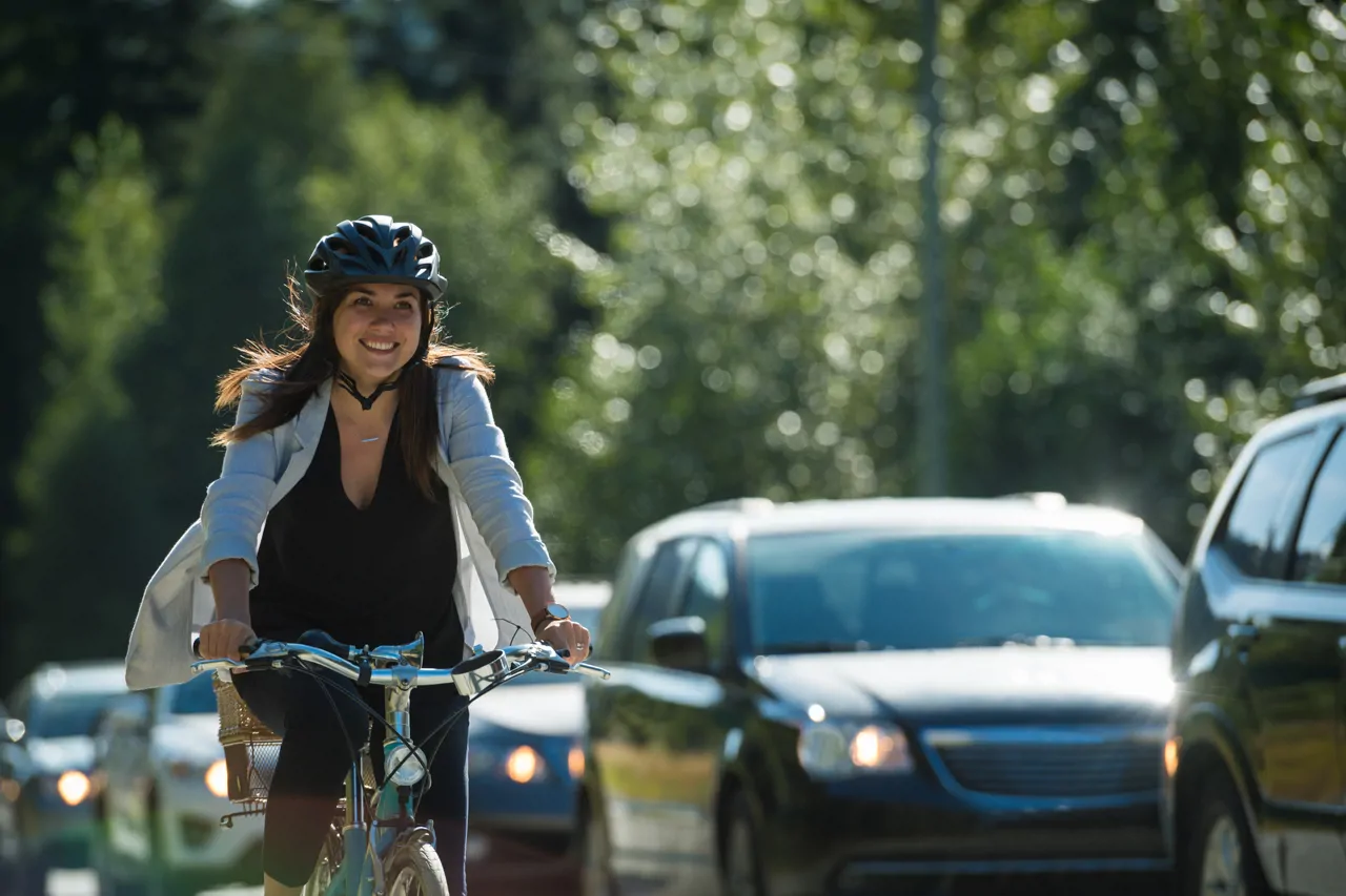 Woman on a bicycle smiling as she cycles past traffic