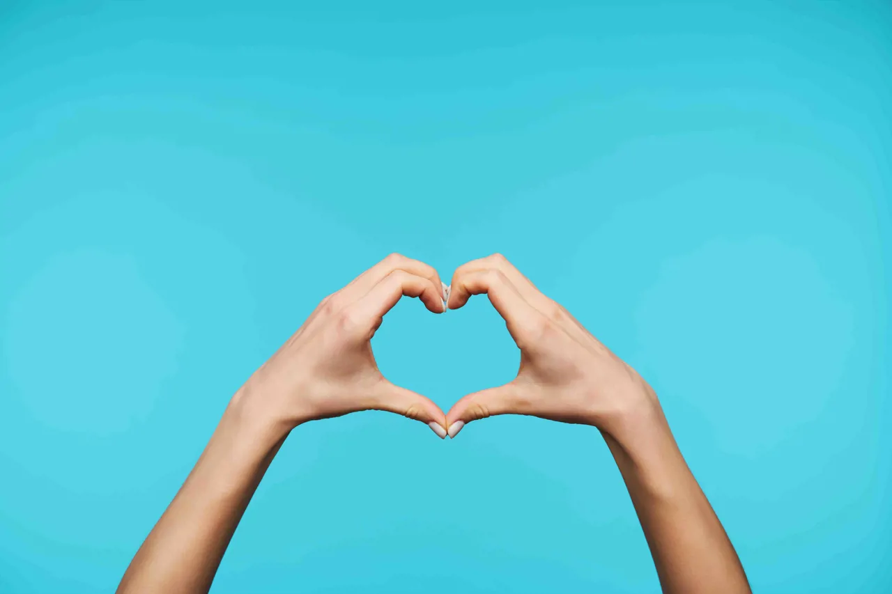 Hands making a heart on a blue background