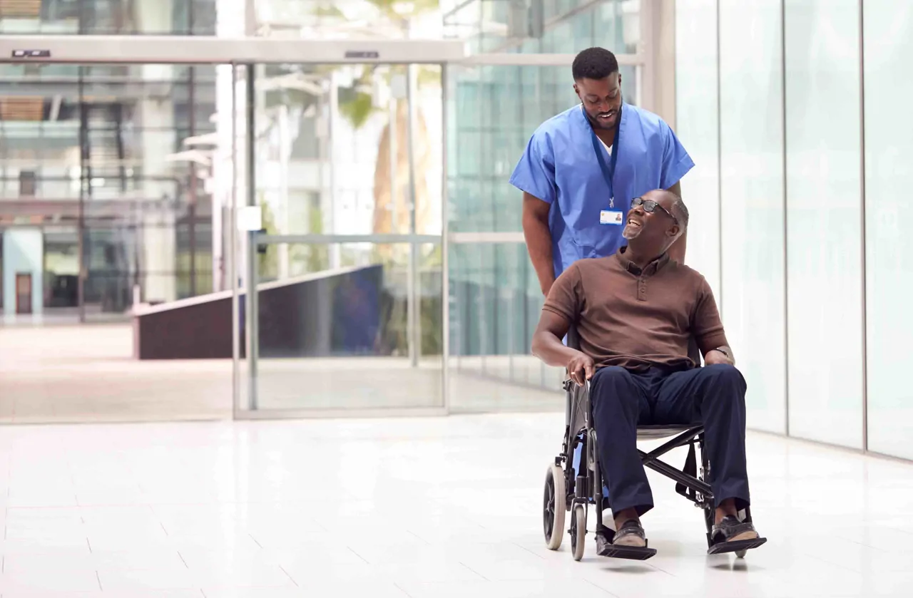 Hospital porter helping a gentleman in a wheelchair