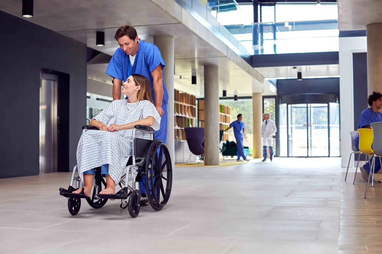 Hospital porter helping a female patient in a wheelchair. 