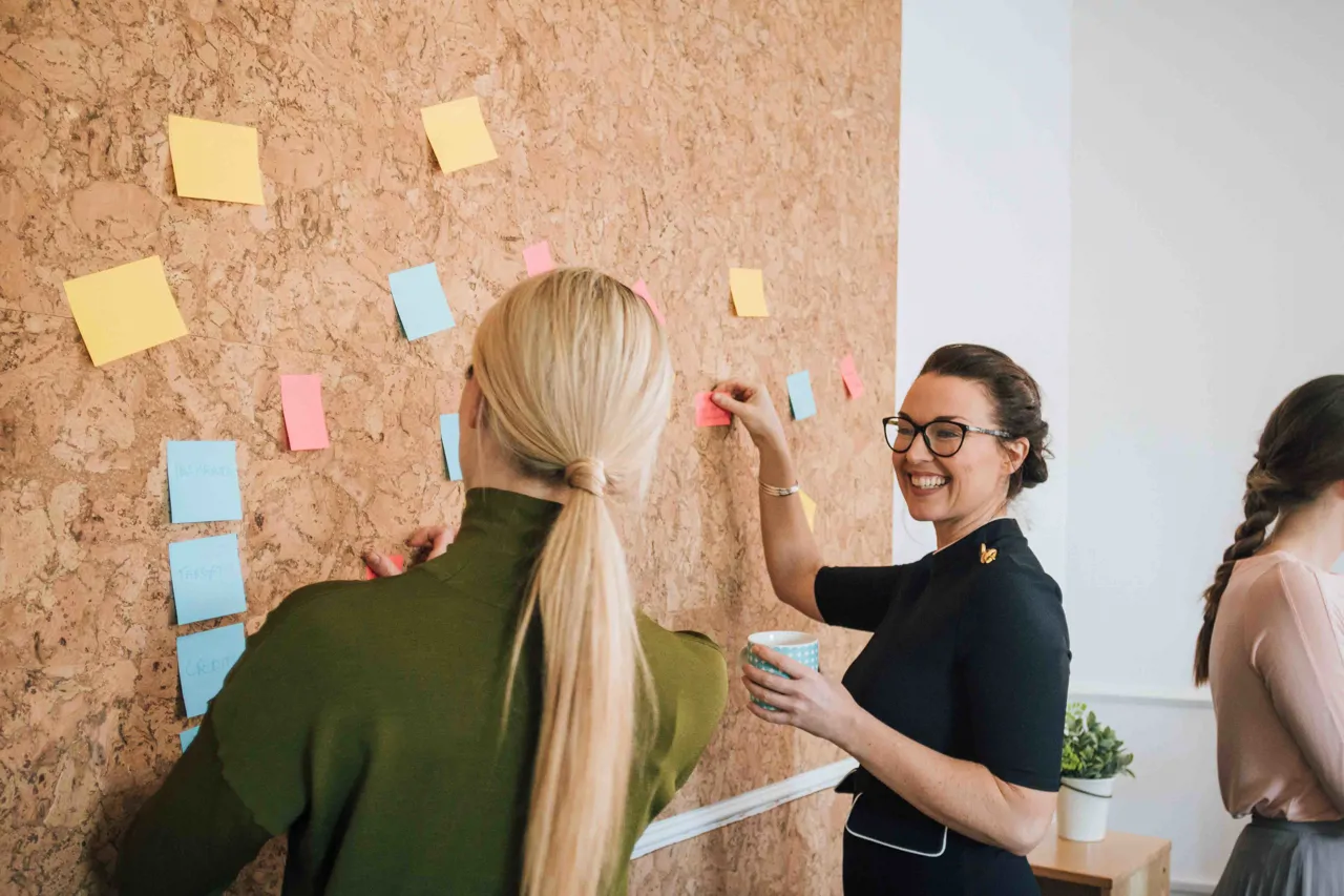 Two female marketing professionals using sticky notes to plan work