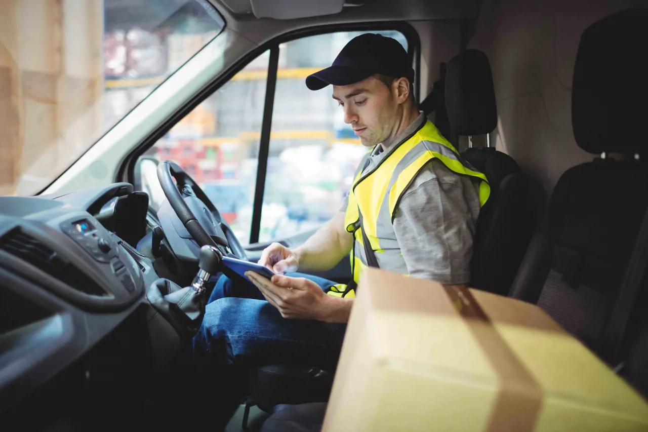 A driver with package looking at paperwork