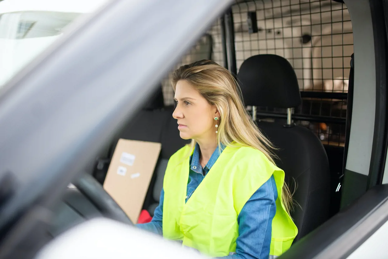 Woman wearing high-vis in delivery van holding parcel
